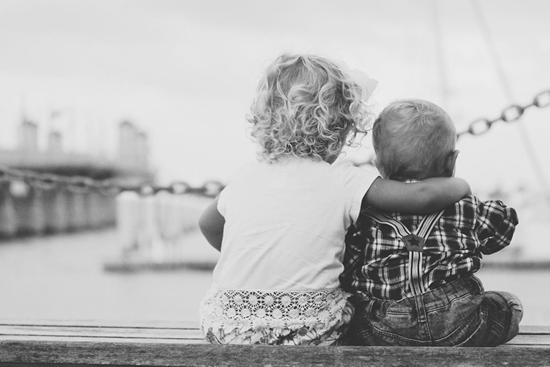 Young girl with her arm around her younger brother