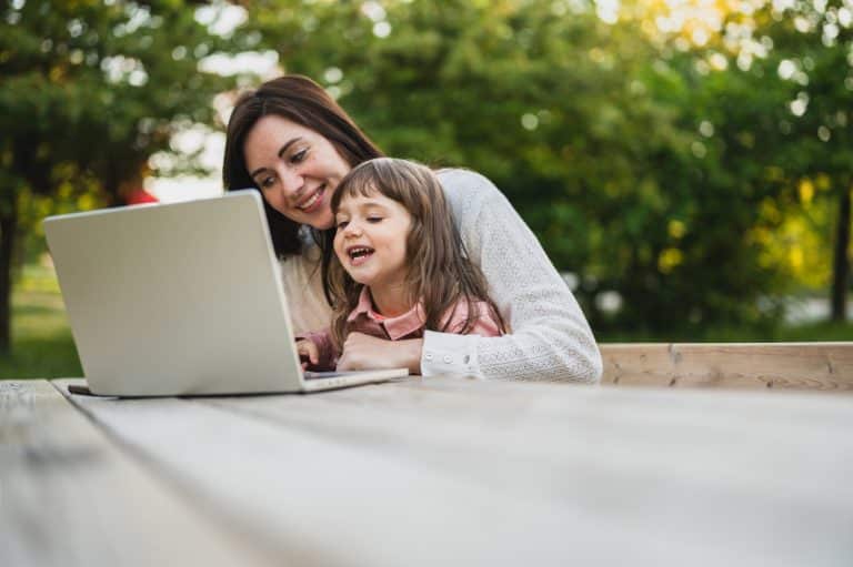 Mother and daughter using laptop. laptop computer education mother children. Mother working remotely with daughter. happy family smiling during having video calling chat on laptop outdoors.