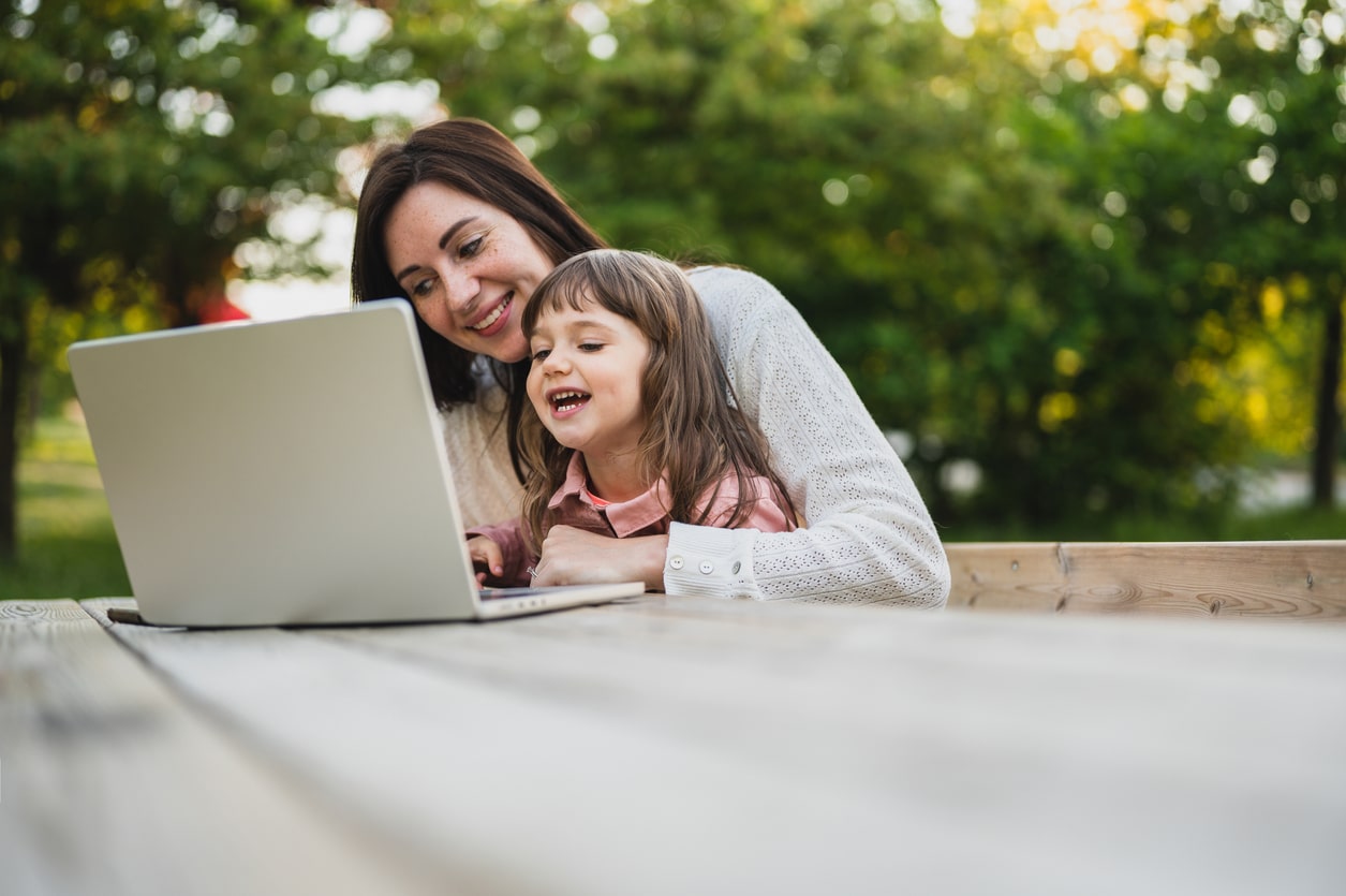 Mother and daughter using laptop. laptop computer education mother children. Mother working remotely with daughter. happy family smiling during having video calling chat on laptop outdoors.