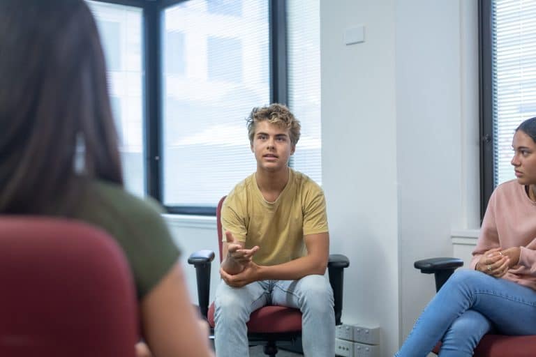 A teenage boy seeking counseling at his school talks while attending a group therapy session.