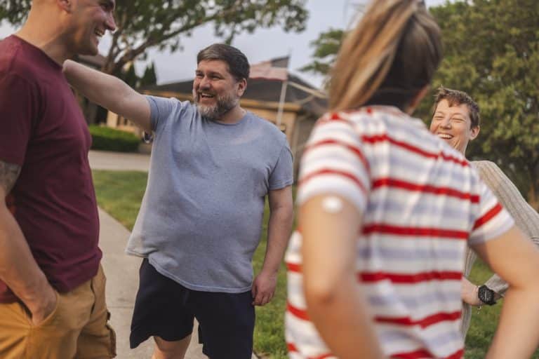 A smaller group of cheerful people talking and laughing while hanging out in the neighborhood.