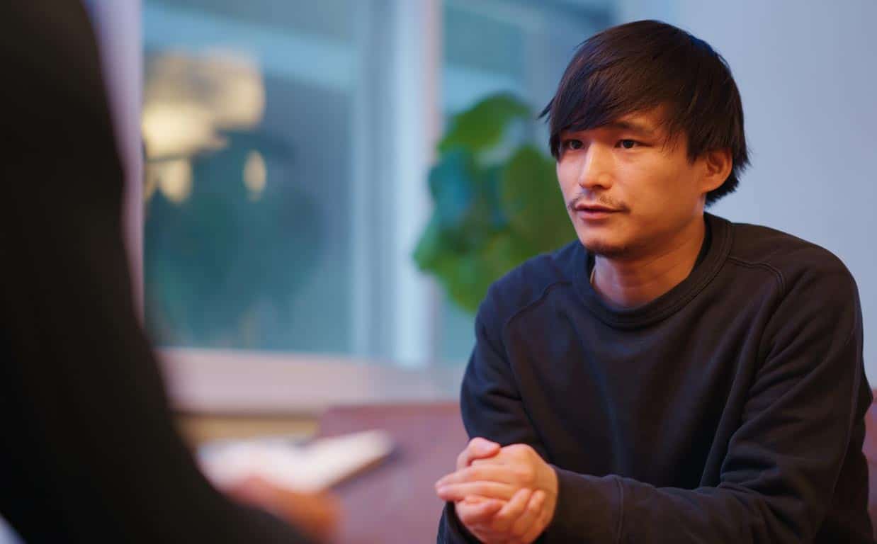 A man looks concerned as he speaks to a faceless counsellor.
